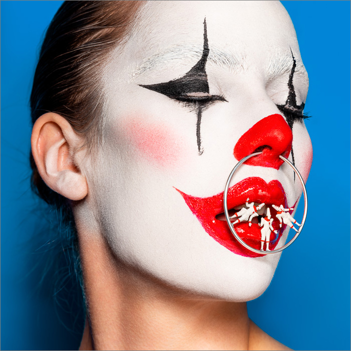 Surreal clown portrait of a female clown, eyes closed, with Pierrots balancing on a silver nose ring—mysterious, dreamlike, theatrical.