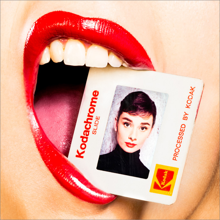 Audrey Hepburn Kodachrome artwork of a stylish woman with red lips holding a photo of the iconic actress gently between her teeth.
