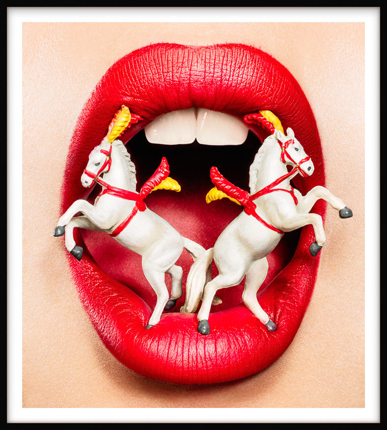 Framed artwork shows 2 miniature ornate white circus horses, prancing on full red lips of wide open woman's mouth with white teeth.
