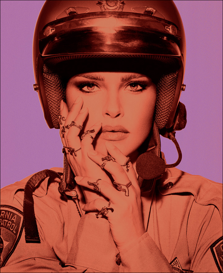 Bold colored B&W artwork of a young female police officer with gun rings, exploring strength, gender, and authority in modern society.