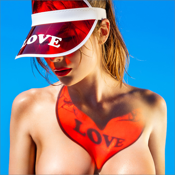 Vibrant red love heart projection on skin through red visor, radiant Miami sunlight creating sensual, summer vibes with golden glow.