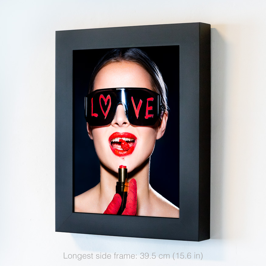 Jet set girl with broken lipstick, bold red lips, Versace sunglasses with 'LOVE' in red lipstick, and playful smile in dramatic light.