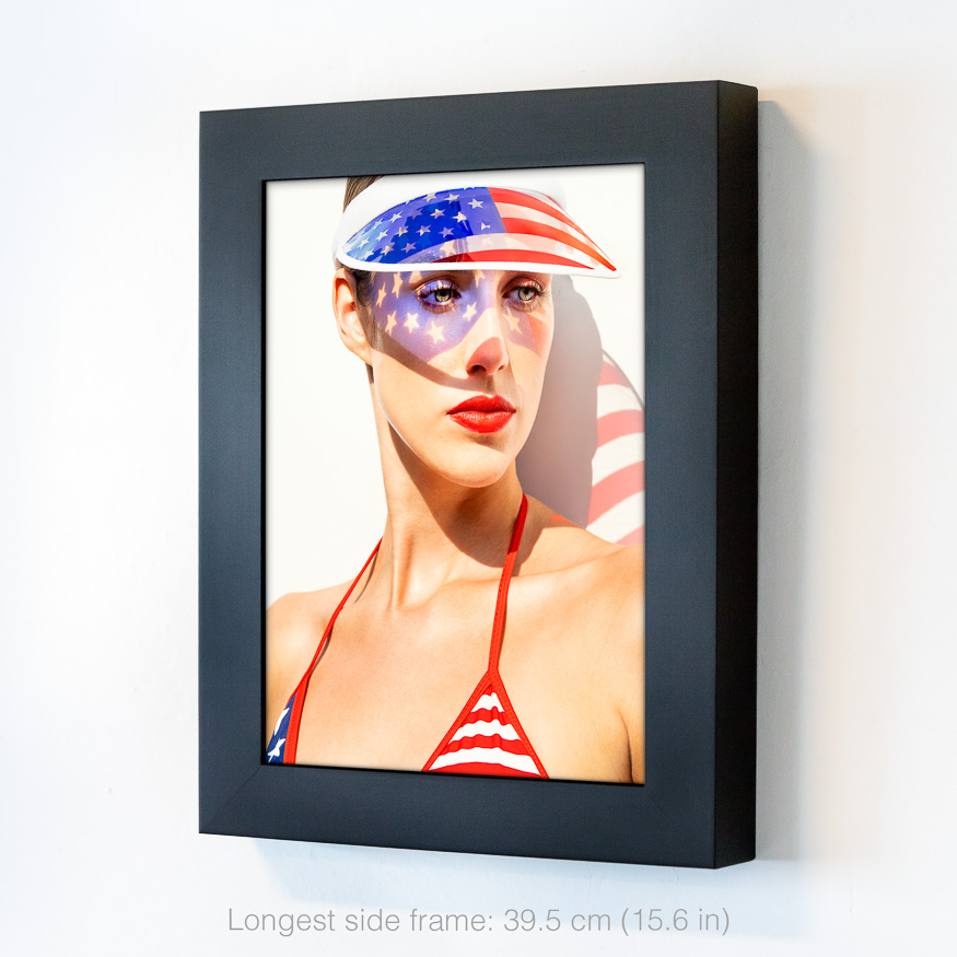 US flag visor casts stars and stripes on woman’s face; red light hits her nose, adding irony to this take on identity and nationalism.
