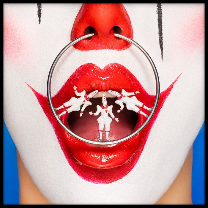 Surreal clown with Pierrots nose ring, balancing in dramatic tension, exploring performance, rivalry and line between humor and danger.
