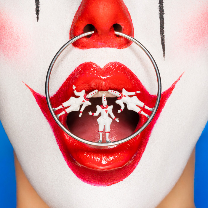 Surreal clown with Pierrots nose ring, balancing in dramatic tension, exploring performance, rivalry and line between humor and danger.