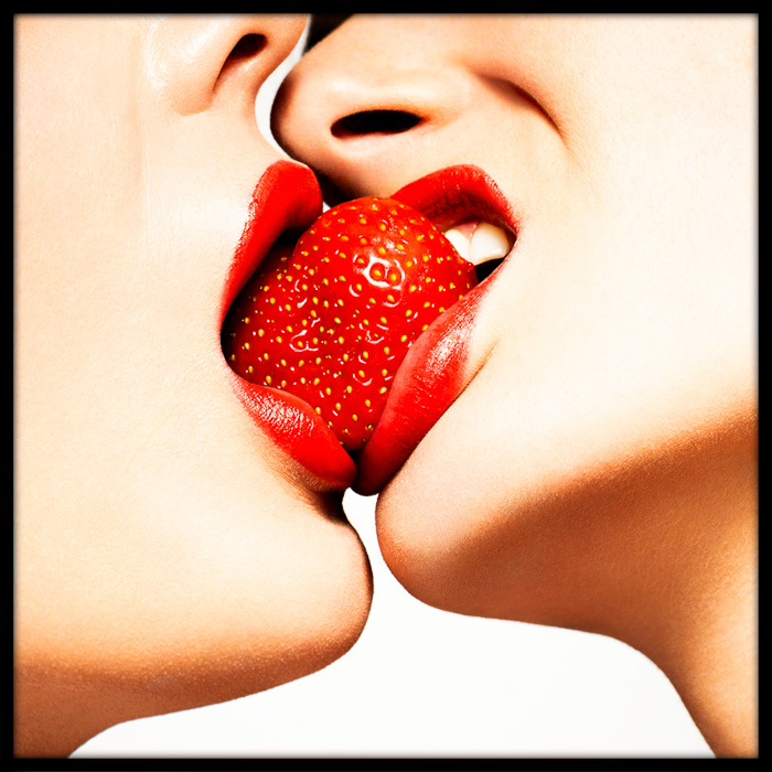 Red Kiss strawberry close-up, showcasing sensuality and passion as two women share a strawberry, symbolizing intimacy and desire.