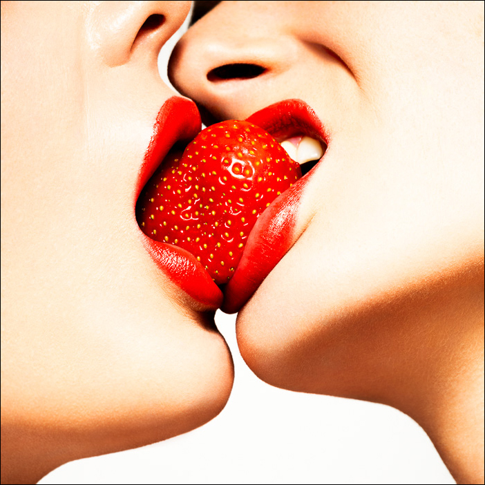 Red Kiss strawberry close-up, showcasing sensuality and passion as two women share a strawberry, symbolizing intimacy and desire.